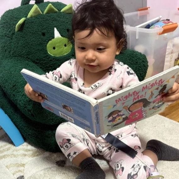 Child exploring a book during an early literacy activity at Sweet Angels