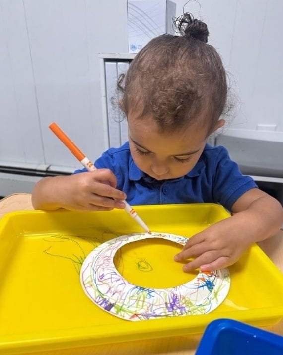 Child doing an art activity at Sweet Angels Daycare