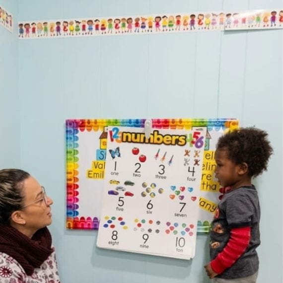 Child learning numbers with an educator during an early math activity at Sweet Angels