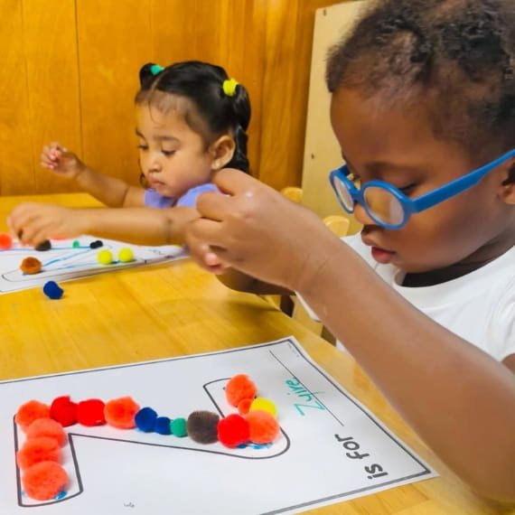 Children developing fine motor skills through a hands-on learning activity at Sweet Angels Daycare & Preschool Center