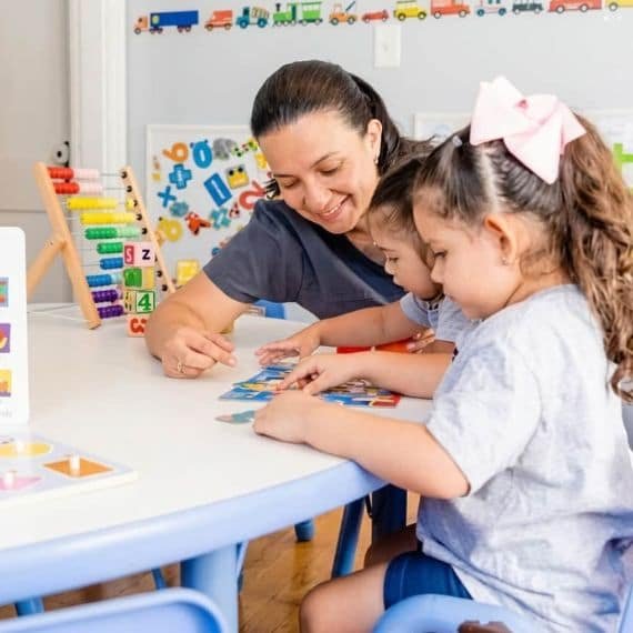 Teacher guiding children during an early literacy activity at Sweet Angels Daycare & Preschool Center