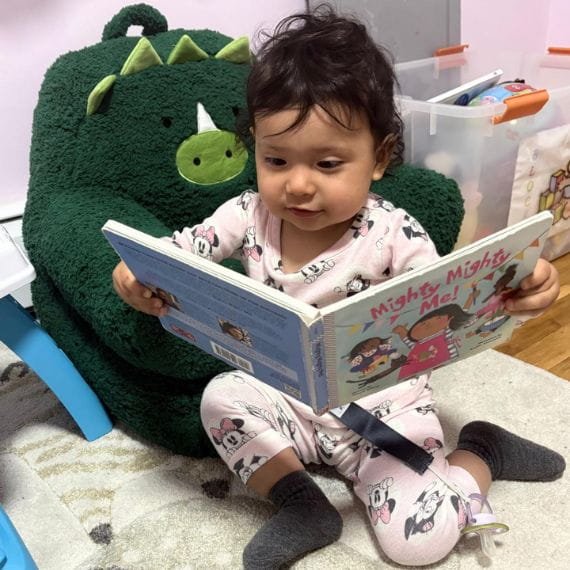 Young child looking at a picture book at Sweet Angels Daycare & Preschool Center