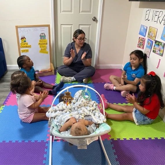 Educator interacting with children during a classroom activity at Sweet Angels Daycare & Preschool Center