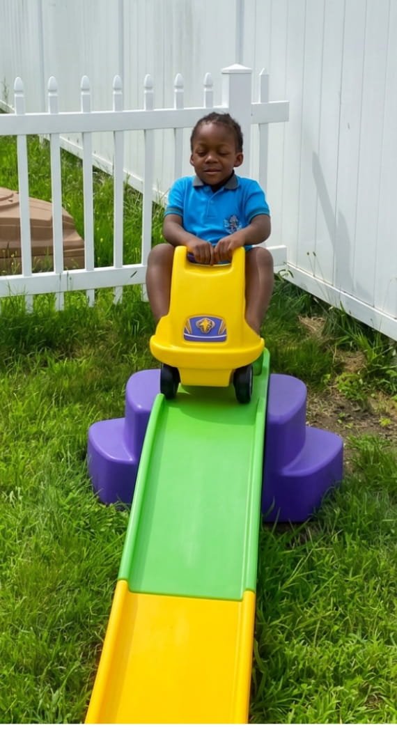 Child enjoying outdoor play on a slide at Sweet Angels Daycare & Preschool Center