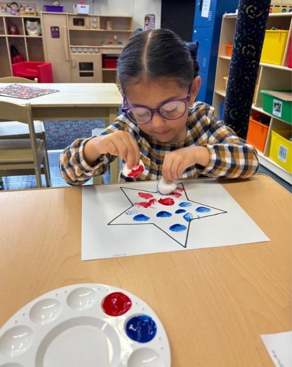 Girl painting a star during an art activity at Sweet Angels Daycare in Everett, MA