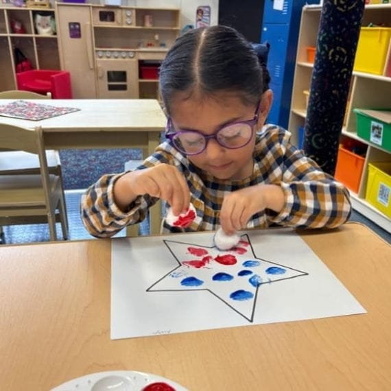 Child painting during an arts and crafts activity at Sweet Angels