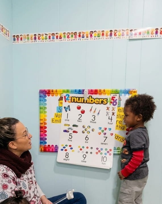 Teacher guiding a child in a number activity at Sweet Angels Daycare in Everett, MA